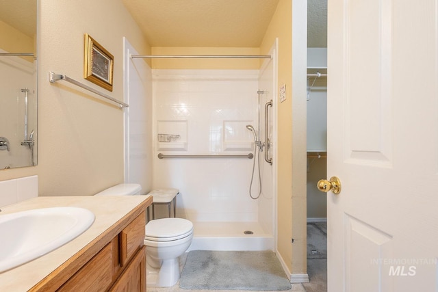 bathroom with toilet, a shower, a textured ceiling, and vanity