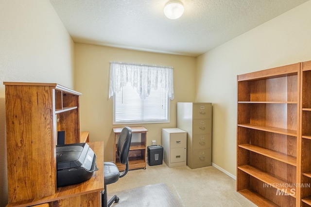 carpeted office with a textured ceiling and baseboards