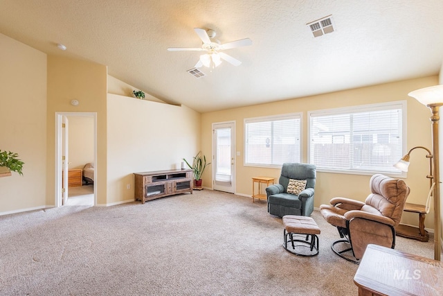 sitting room featuring vaulted ceiling, carpet floors, a textured ceiling, and visible vents