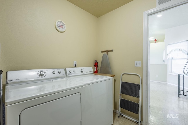 washroom with laundry area, separate washer and dryer, heating unit, and baseboards