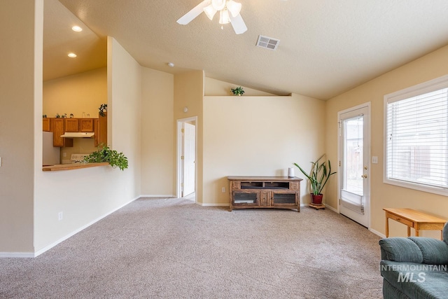 living area featuring light carpet, baseboards, visible vents, and vaulted ceiling