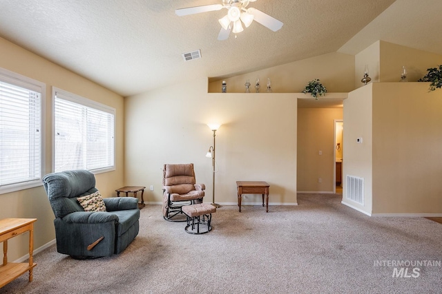 sitting room with vaulted ceiling, carpet floors, a textured ceiling, and visible vents