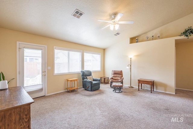 sitting room with lofted ceiling, a textured ceiling, carpet, and visible vents