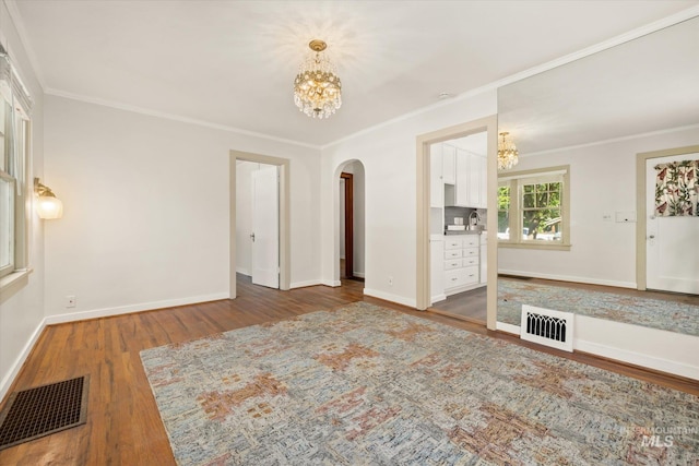 1806 N 28th St, Boise, ID 83703 - unfurnished living room featuring a chandelier, arched walkways, wood finished floors, baseboards, and crown molding