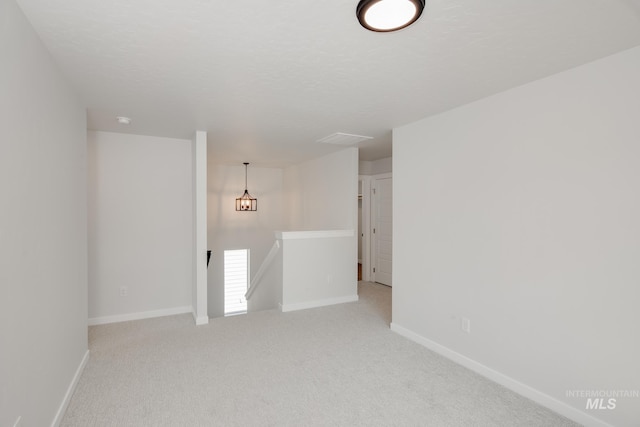 spare room featuring visible vents, light colored carpet, a textured ceiling, and baseboards