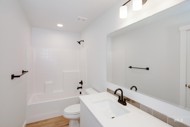 full bathroom with visible vents, toilet, washtub / shower combination, vanity, and wood finished floors