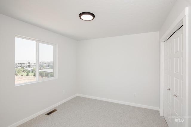 unfurnished bedroom featuring a closet, visible vents, light carpet, and baseboards