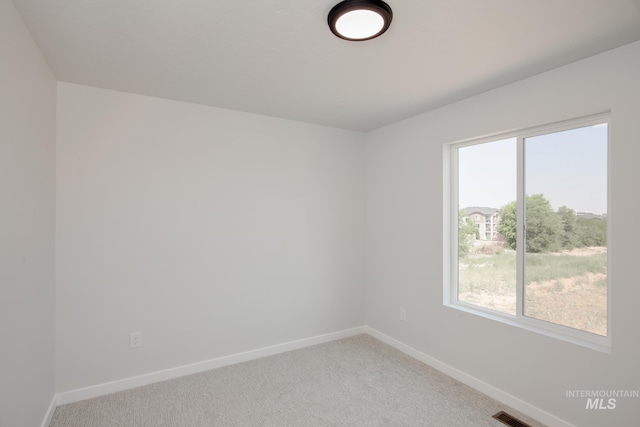 carpeted spare room featuring baseboards