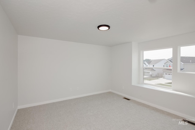 carpeted spare room featuring visible vents and baseboards