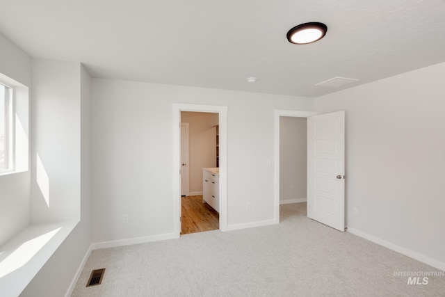 unfurnished bedroom with light colored carpet, visible vents, and baseboards