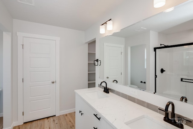 full bath featuring toilet, visible vents, a sink, and wood finished floors