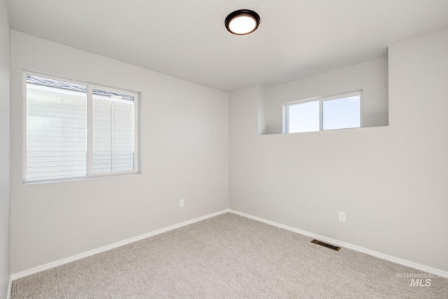 carpeted empty room featuring visible vents and baseboards