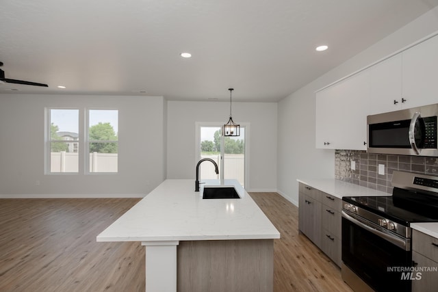 kitchen featuring hanging light fixtures, a kitchen island with sink, appliances with stainless steel finishes, and a sink