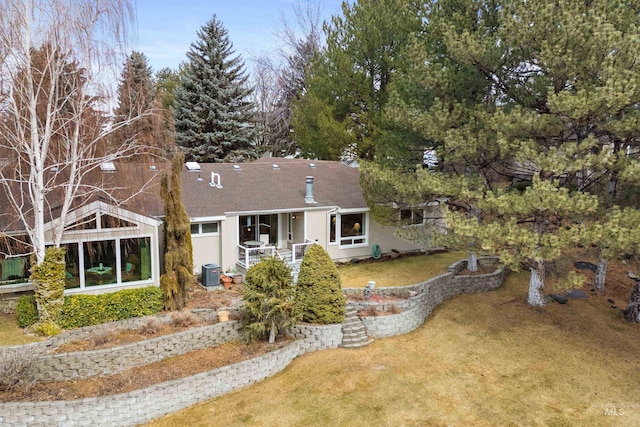 rear view of house with stucco siding, a shingled roof, central AC, and a yard