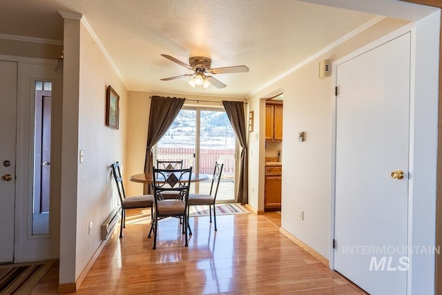 dining area with light wood finished floors, a textured ceiling, a baseboard heating unit, and a ceiling fan