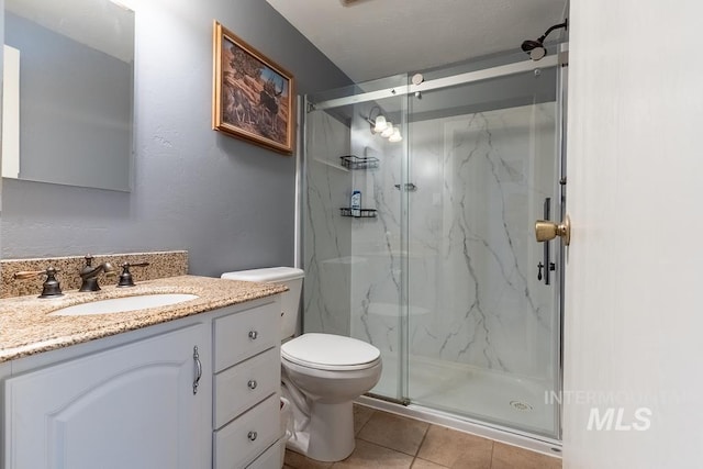 bathroom featuring a marble finish shower, toilet, vanity, and tile patterned flooring