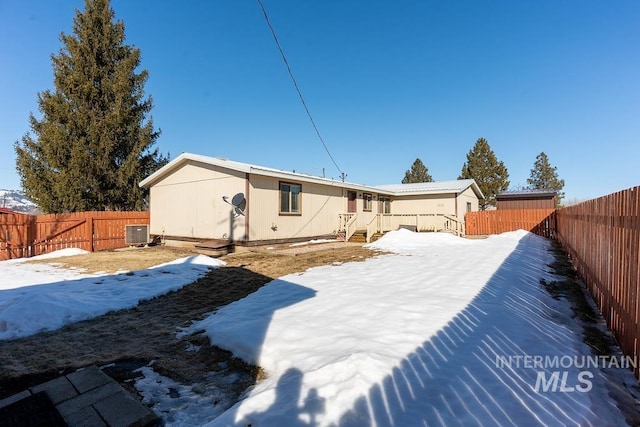 snow covered property featuring central AC and a fenced backyard