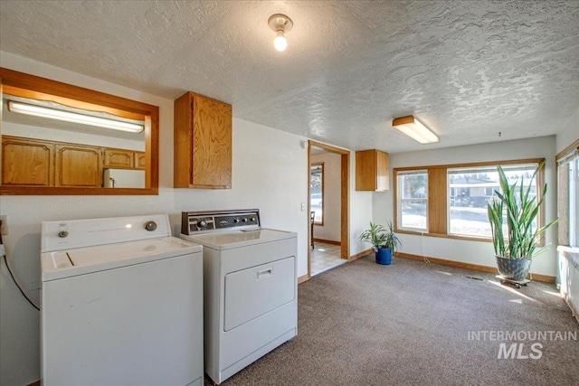 laundry room with carpet, baseboards, cabinet space, a textured ceiling, and washer and dryer