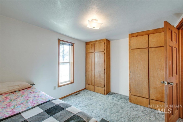 unfurnished bedroom featuring a textured ceiling, visible vents, a closet, and light carpet