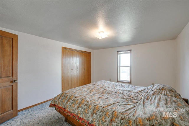 bedroom with a closet, baseboards, carpet floors, and a textured ceiling