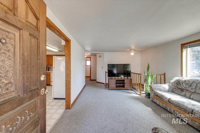 living area with baseboards, light colored carpet, a textured ceiling, and a ceiling fan