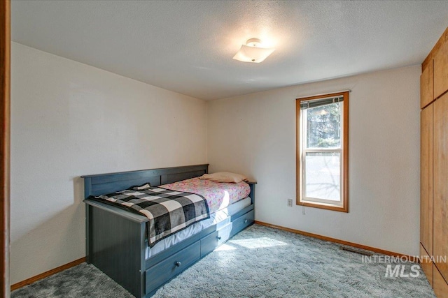 bedroom featuring a textured ceiling, baseboards, and carpet