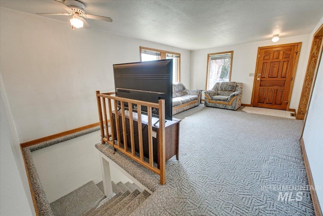 carpeted living area featuring baseboards and a textured ceiling