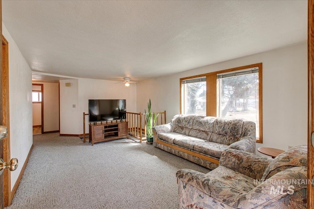 living area featuring a textured ceiling, baseboards, a wealth of natural light, and light carpet