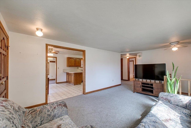 living area featuring ceiling fan, baseboards, and a textured ceiling