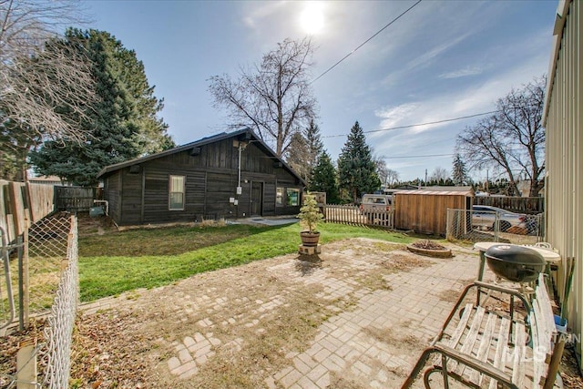 view of patio featuring an outbuilding, a fenced backyard, and an outdoor fire pit