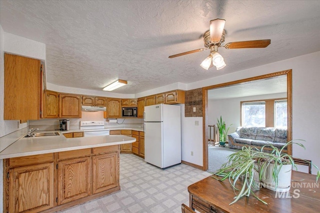 kitchen with under cabinet range hood, light floors, light countertops, a peninsula, and white appliances