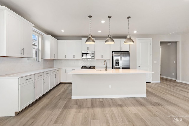 kitchen featuring a sink, decorative backsplash, light countertops, light wood-style floors, and appliances with stainless steel finishes