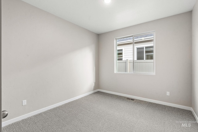 carpeted spare room with visible vents and baseboards