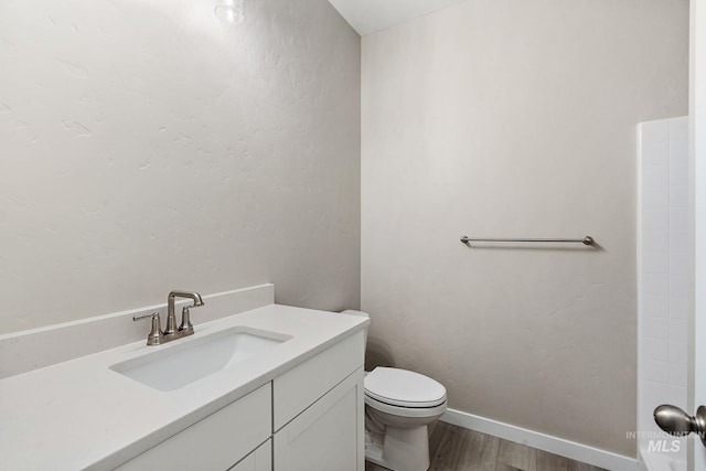 bathroom featuring vanity, toilet, wood finished floors, and baseboards