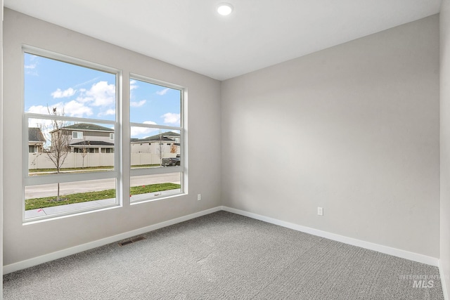 spare room with carpet, visible vents, and baseboards