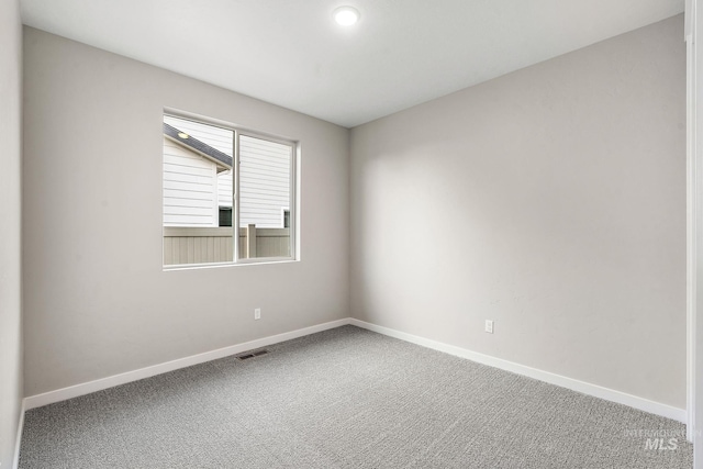 spare room featuring baseboards, visible vents, and carpet floors