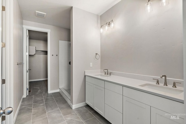 full bath with visible vents, tiled shower, a walk in closet, and a sink