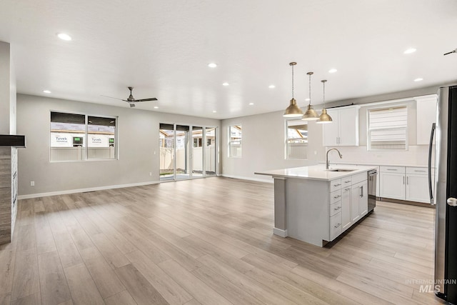 kitchen featuring a kitchen island with sink, light wood-style flooring, a sink, open floor plan, and freestanding refrigerator