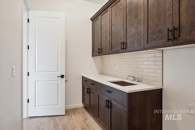 6139 W Burnt Sage Dr, Meridian, ID 83646 - interior space featuring light countertops, dark brown cabinets, decorative backsplash, light wood finished floors, and a sink