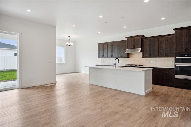 6139 W Burnt Sage Dr, Meridian, ID 83646 - kitchen with an inviting chandelier, a sink, gas stovetop, under cabinet range hood, and double oven