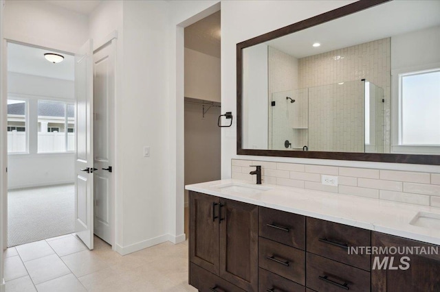 6139 W Burnt Sage Dr, Meridian, ID 83646 - full bathroom featuring double vanity, a stall shower, a walk in closet, decorative backsplash, and a sink
