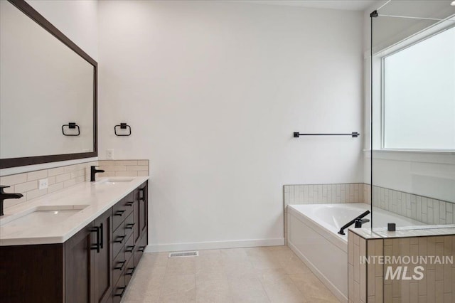 6139 W Burnt Sage Dr, Meridian, ID 83646 - full bath featuring a garden tub, baseboards, a sink, and backsplash