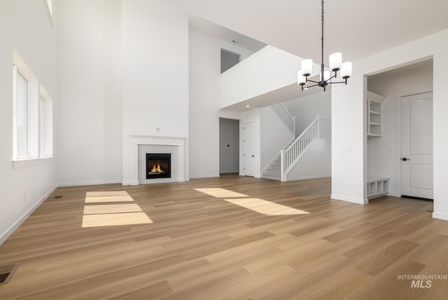 9124 W Patmore Ct, Star, ID 83669 - unfurnished living room featuring a chandelier, a high ceiling, light wood-style floors, baseboards, and stairway
