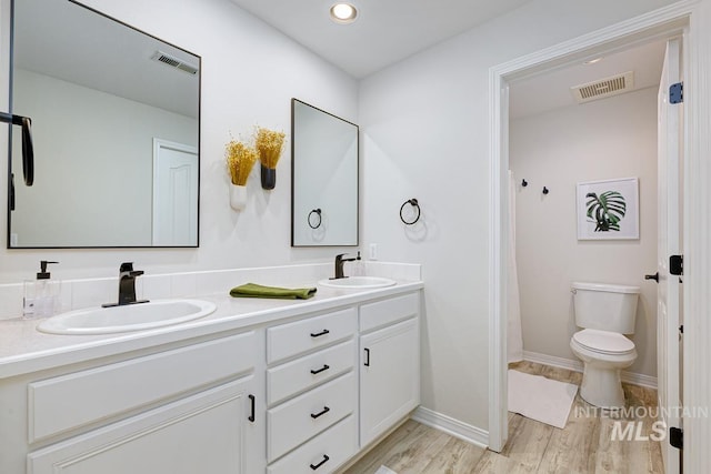 5158 S Surprise Way, Boise, ID 83716 - bathroom with double vanity, toilet, wood finished floors, baseboards, and recessed lighting
