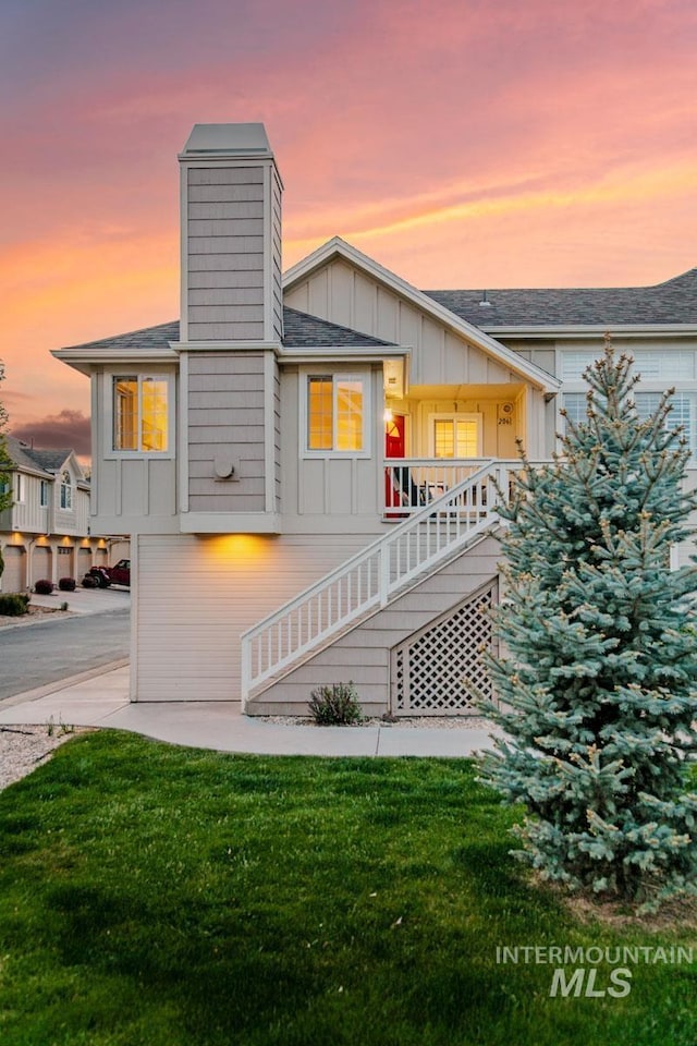 5158 S Surprise Way, Boise, ID 83716 - back of property at dusk featuring board and batten siding, a yard, stairs, and roof with shingles