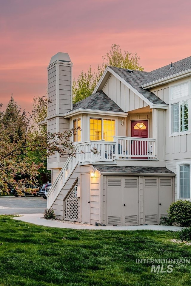5158 S Surprise Way, Boise, ID 83716 - back of house at dusk featuring stairs, board and batten siding, a chimney, and a yard