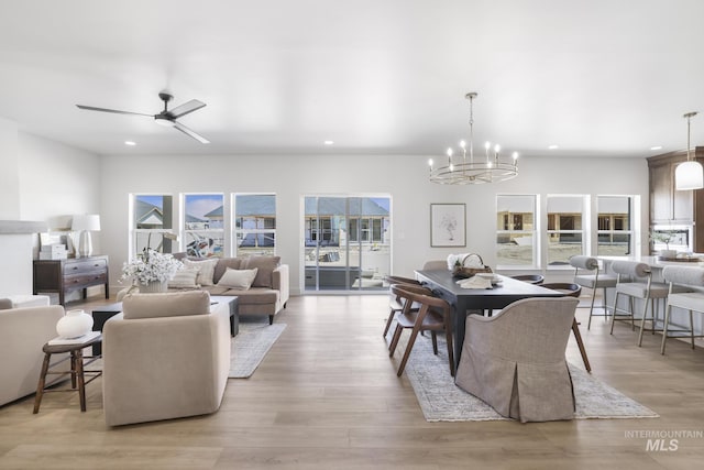 dining space featuring light wood-type flooring, recessed lighting, and ceiling fan with notable chandelier
