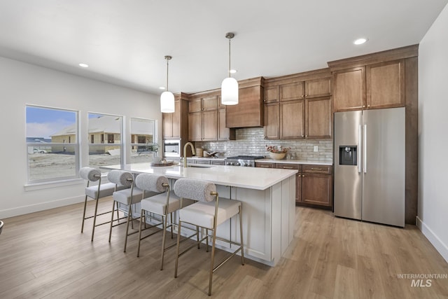 kitchen with a sink, stainless steel fridge, baseboards, custom range hood, and range