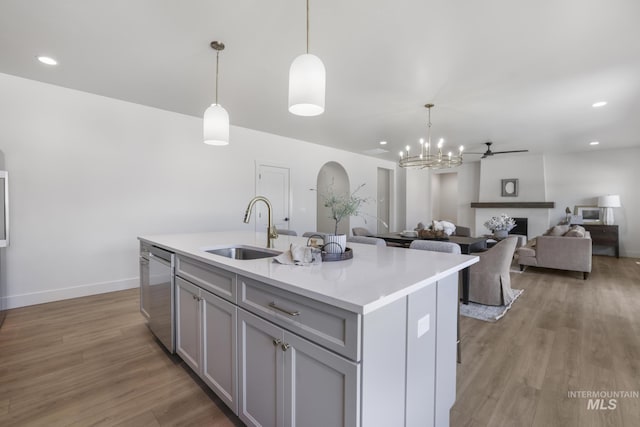 kitchen featuring a sink, an inviting chandelier, light wood-style floors, gray cabinetry, and dishwasher