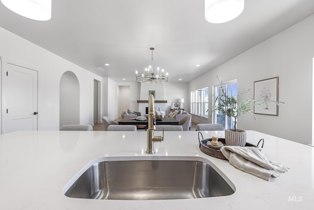 kitchen featuring open floor plan, a sink, recessed lighting, and hanging light fixtures